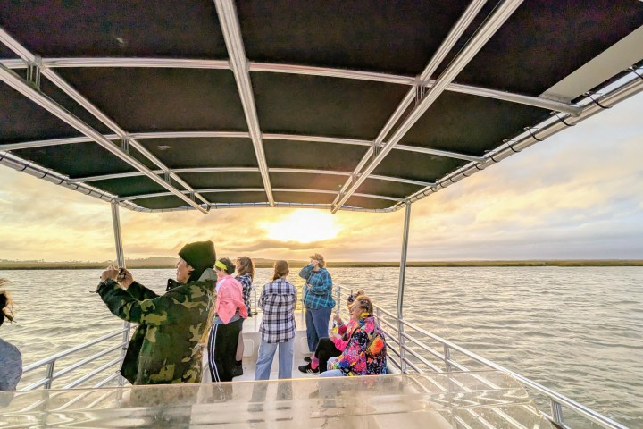 People on a boat at sunset, taking photos and enjoying the view over the water.