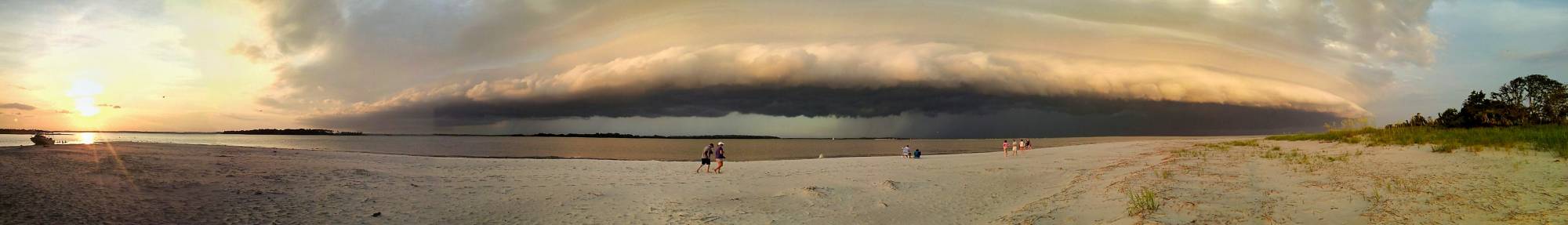 Shelf Cloud Panoramic view of beach with dramatic storm clouds and sunset.
