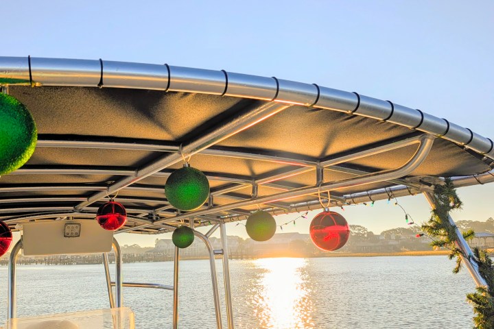 Boat deck decorated with Christmas ornaments and garlands on a sunny day.