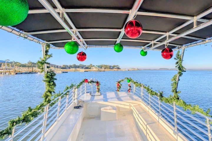 Boat deck with Christmas decorations, green and red ornaments, garlands, and water view.