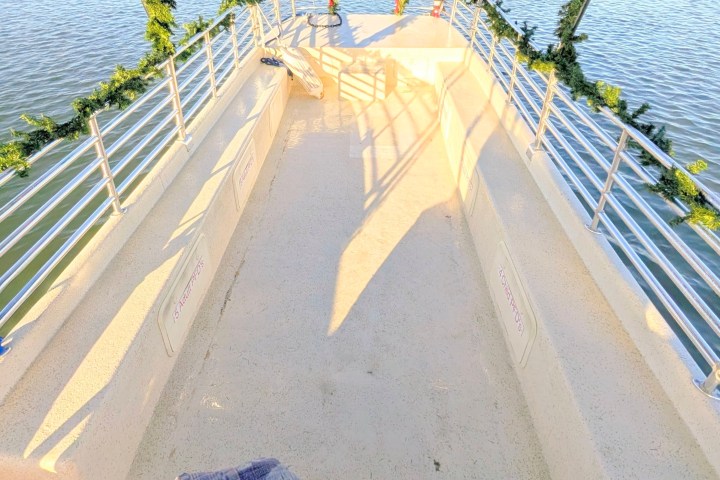 Decorated boat with Christmas ornaments and cookies on a table, sailing on calm water.